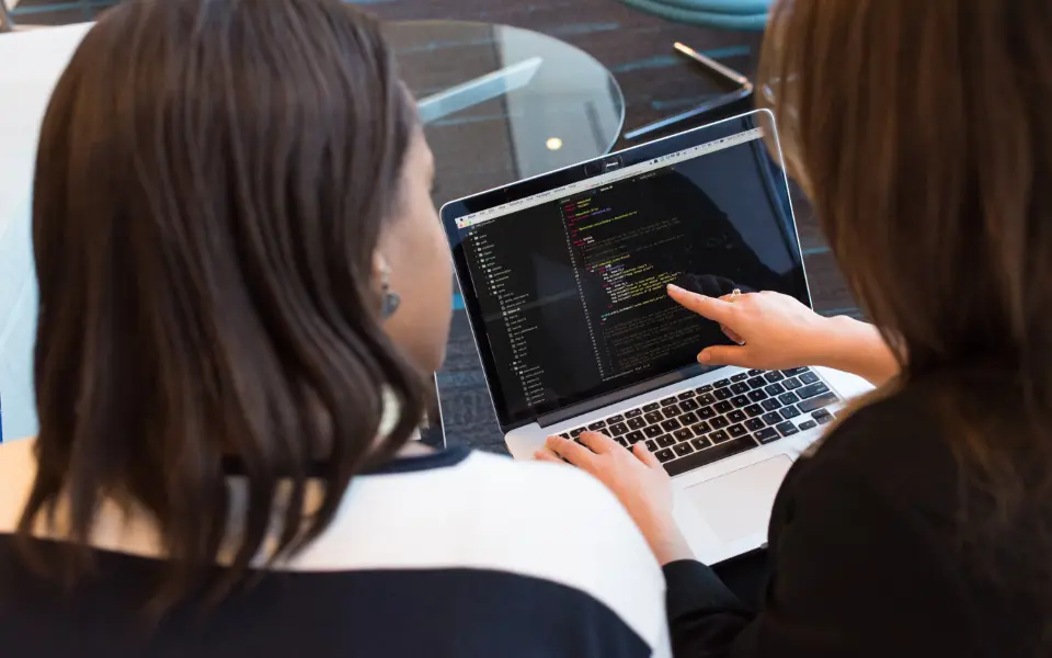 Two people reviewing code on a laptop